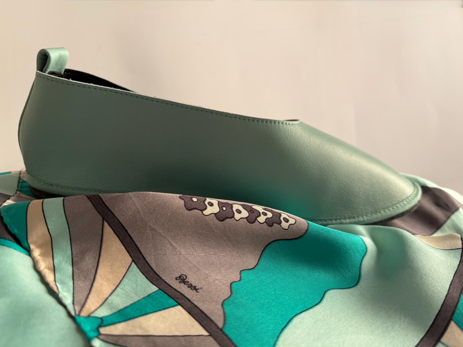 Calzatura artigianale AMR in pelle verde salvia poggiata su un foulard stampato